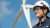 Woman wearing safety gear standing near a wind turbine